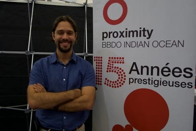 David in front of a banner about Proximity BBDO 15 years of success at the Job Fair